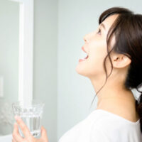 洗面所でうがいをする女