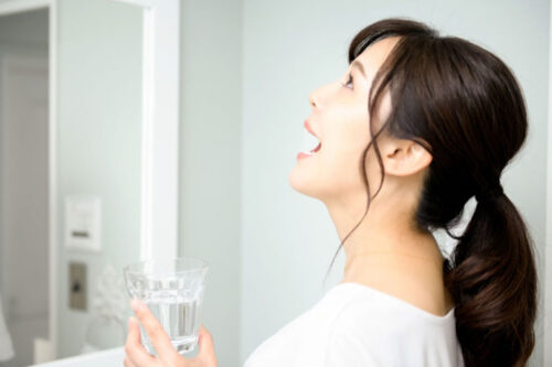 洗面所でうがいをする女