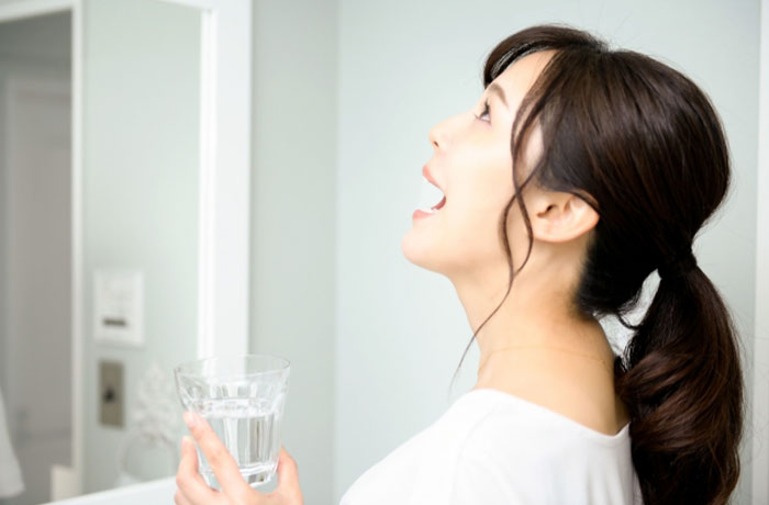 洗面所でうがいをする女